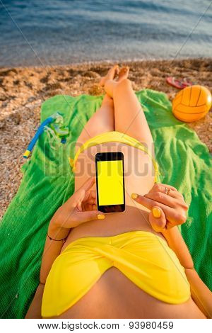 Woman using mobile phone on the beach