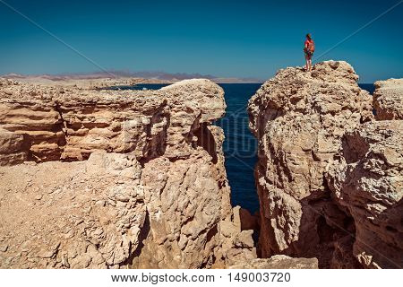 Young lady standing on the top of the cliff in the National Park of Ras Muhammad, Egypt
