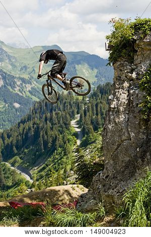 Extreme freeride mountainbiker jumping from a rock