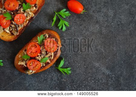 Toasts with sprats tomato and garlic on a black background with space for text background food
