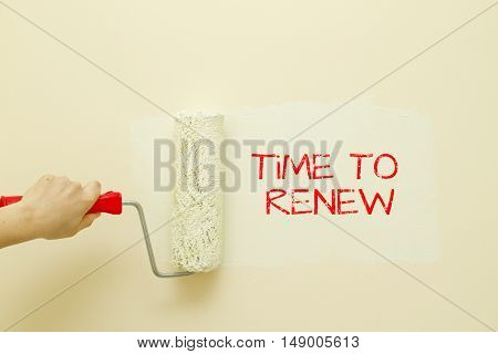 Woman hand painting wall written Time to renew on it.