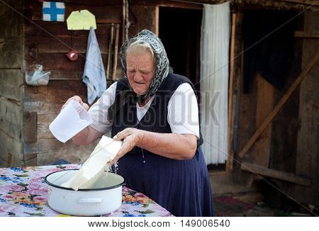 SALCIUA, ROMANIA - SEPTEMBER 14, 2016: Old woman selling cheese at the farm in the mountains