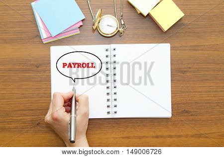 Hand writing PAYROLL word on a notebook with pen.