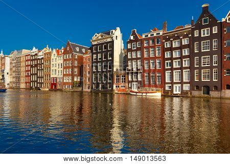 Beautiful typical Dutch dancing houses at the Amsterdam canal Damrak in sunny day, Holland, Netherlands.