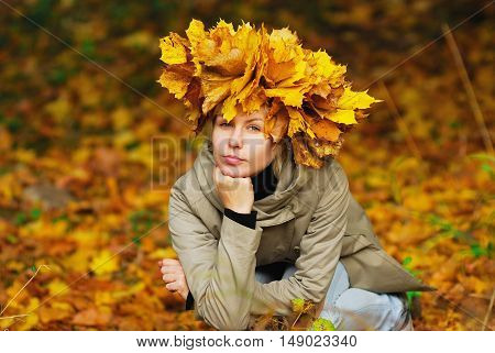 beautiful young girl in autumn park with wreath of leaves close-up.