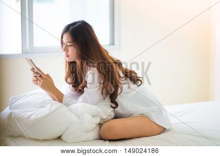 Girl Using A Mobile Phone Lying On The Bed At Home
