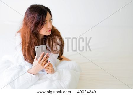 Girl Using A Mobile Phone Lying On The Bed At Home