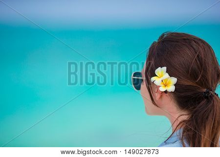 Young beautiful woman during tropical beach vacation. Enjoy suumer vacation alone on the beach at Africa with frangipani flowers in her hair