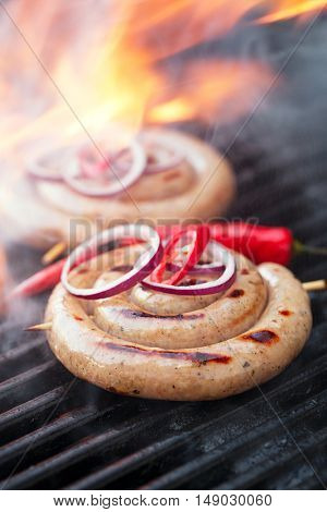 cumberland sausage, spiral pork sausage on bbq grill with flame, homemade