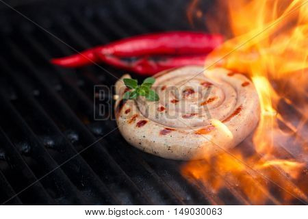 cumberland sausage, spiral pork sausage on bbq grill with flame, homemade
