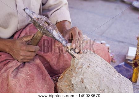 Artisan makes pieces for mosaic craftwork. He is shaping pieces from glazed tiles