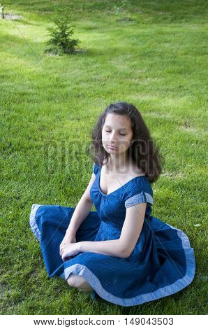 Girl sitting with closed eyes on the lawn