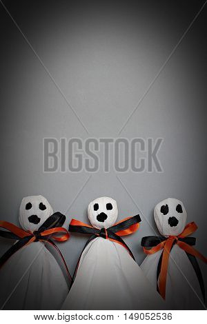 Halloween concept background : Three halloween ghosts DIY made from white tissue paper, black and orange ribbon on gray background