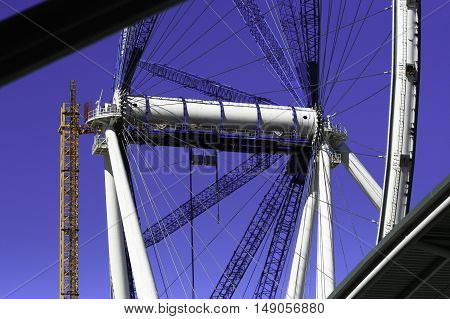 A very large ferris wheel under construction against a blue sky
