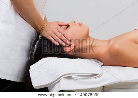 Massagist with woman patient in aroma spa wellness center. Professional face lifting massage to beautiful girl in cosmetology cabinet or beauty parlor.