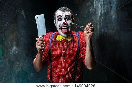 The scary clown holding a knife on dack. Halloween concept of horror and murderer