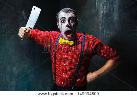 The scary clown holding a knife on dack. Halloween concept of horror and murderer