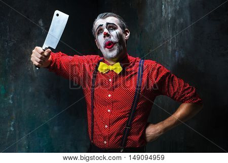 The scary clown holding a knife on dack. Halloween concept of horror and murderer