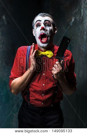 The scary clown holding a knife on dack. Halloween concept of horror and murderer