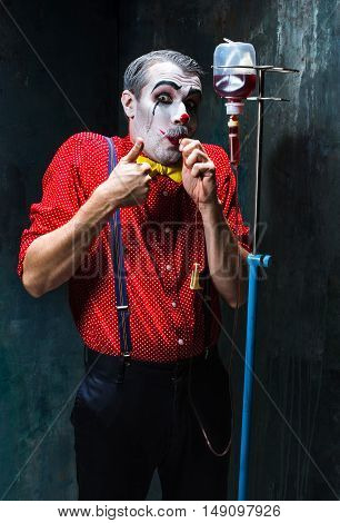 The scary clown and drip with blood on dack. Halloween concept of horror and murderer