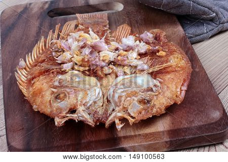 Deep fried fish ,Nile tiapia, with crispy garlic on butcher served. Selective focus
