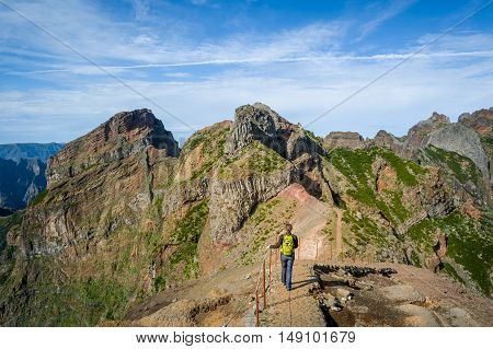 Woman hiker on the dangerous path between the rocky cliffs of Pico Arieiro hiking path. Madeira island, Portugal.