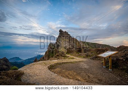 Serpentine road to Pico Arieiro and information sign in the mountain hiking path. Madeira island, Portugal.