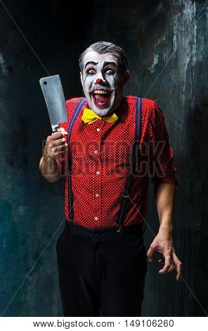 The crazy clown holding a knife on dack. Halloween concept of horror and murderer