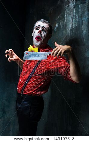 The crazy clown holding a knife on dack. Halloween concept of horror and murderer