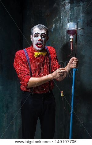 The scary clown and drip with blood on dack. Halloween concept of horror and murderer