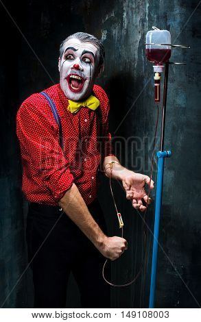 The scary clown and drip with blood on dack. Halloween concept of horror and murderer
