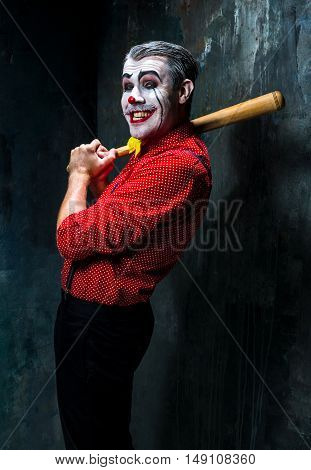 The scary clown and baseball-bat on dack. Halloween concept of horror and murderer