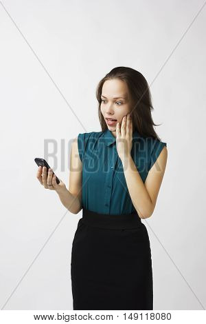 business woman with astonishment looks at the phone on a white background