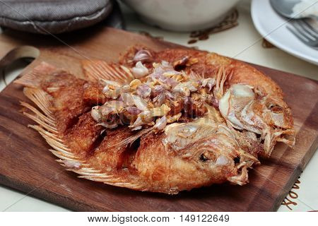 Deep fried fish ,Nile tiapia, with crispy garlic on butcher served. Selective focus