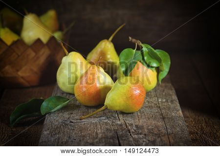 Sweet yellow pears lying on a wooden serface and in a basket behind