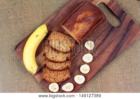 Homemade banana cake with sliced banana and whole banana on butcher served.