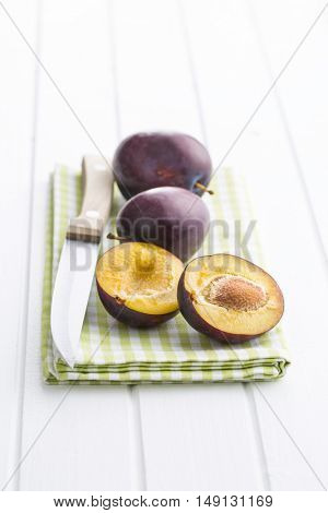 Halved ripe plum on white table.