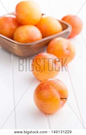 Fresh yellow plums on white table.