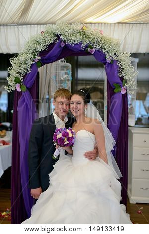 Beauty bride and handsome groom are registering the marriage. Wedding couple is marrying. Beautiful model girl in white dress and in lace veil. Man in suit. Female and male portrait. Cute lady and guy