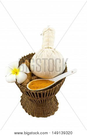 Spa herbal compressing ball white frangipani flowers (Plumeria spp Apocynaceae Pagoda tree Temple tree) turmeric powder in white spoon and candle in bamboo basket on brown fabric sack background