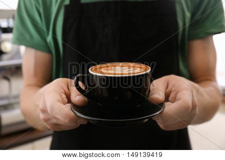 Man holding cup of coffee with latte art
