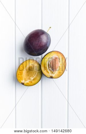 Halved ripe plums on kitchen table. Top view.