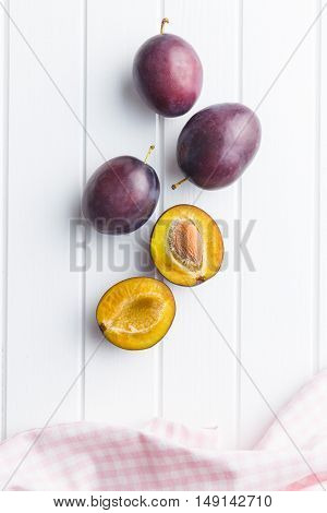 Halved ripe plums on kitchen table. Top view.