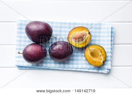 Halved ripe plums on kitchen table. Top view.