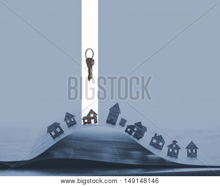 Image of an open newspaper with paper houses on blue background. Above one house stands bunch of keys. House and keys are marked in white.