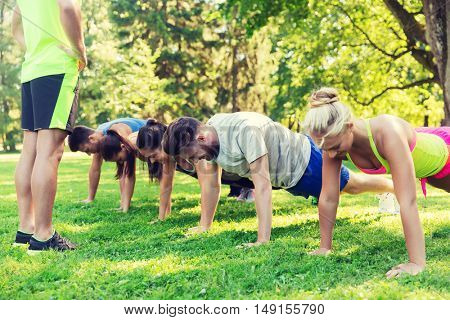 fitness, sport, friendship and healthy lifestyle concept - group of happy teenage friends or sportsmen exercising and doing push-ups at boot camp