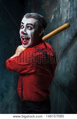 The scary clown and baseball-bat on dack. Halloween concept of horror and murderer