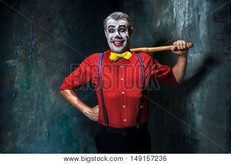 The scary clown and baseball-bat on dack. Halloween concept of horror and murderer