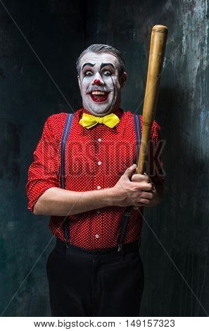 The scary clown and baseball-bat on dack. Halloween concept of horror and murderer