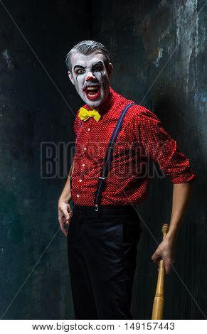 The scary clown and baseball-bat on dack. Halloween concept of horror and murderer